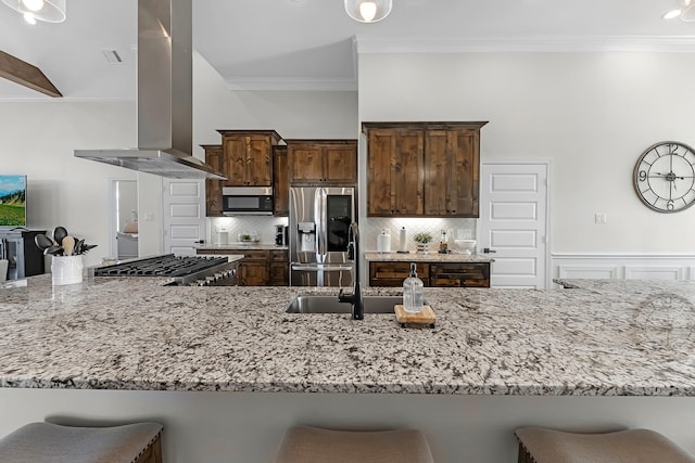 kitchen with stainless steel fridge, a breakfast bar, island range hood, and light stone countertops