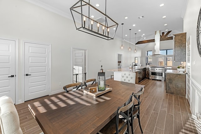 dining space with wood finish floors, visible vents, recessed lighting, crown molding, and a towering ceiling