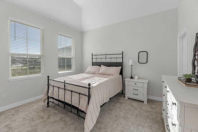 bedroom featuring light colored carpet, baseboards, and vaulted ceiling