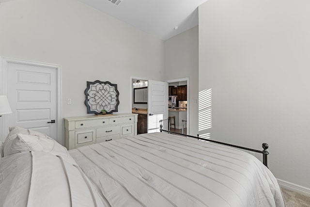 carpeted bedroom featuring visible vents, baseboards, high vaulted ceiling, and ensuite bathroom