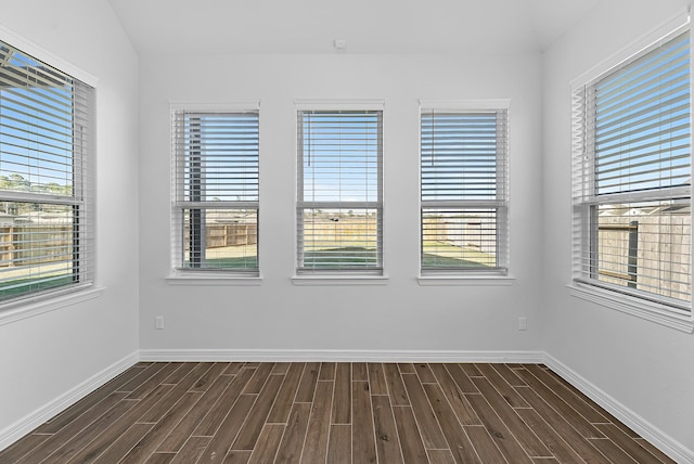 unfurnished room featuring baseboards and dark wood-style flooring