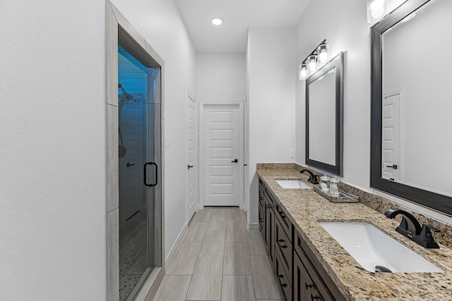 full bath with double vanity, baseboards, a stall shower, and a sink