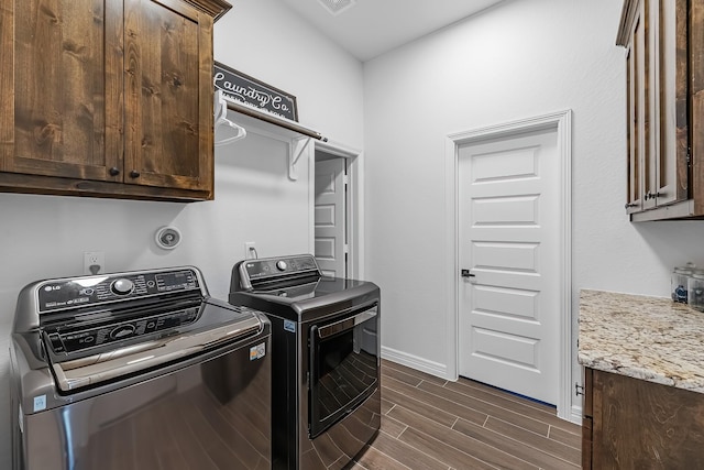 laundry room with wood finish floors, cabinet space, baseboards, and washer and clothes dryer