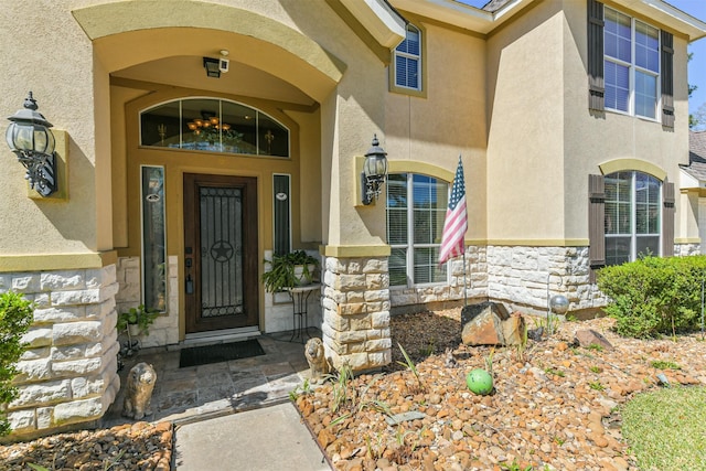 doorway to property featuring stucco siding and stone siding