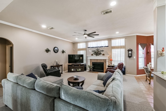 living room featuring crown molding, arched walkways, visible vents, and a tile fireplace