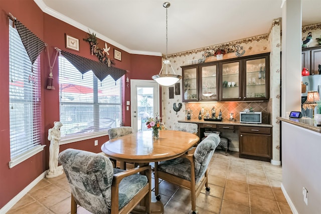 dining area featuring light tile patterned floors, crown molding, and baseboards