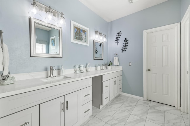 full bath with double vanity, baseboards, marble finish floor, and a sink