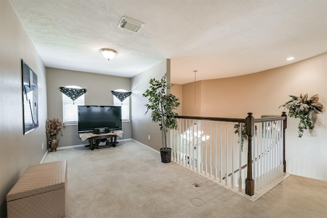 sitting room featuring visible vents, baseboards, carpet, and a textured ceiling