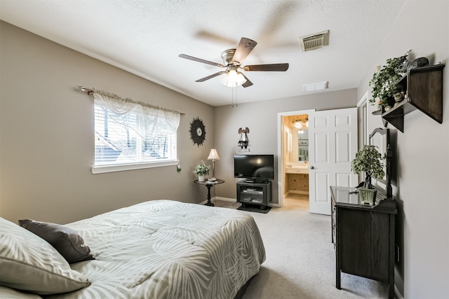 bedroom with visible vents, light carpet, a textured ceiling, and ensuite bath