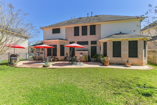 back of house featuring brick siding, fence, a lawn, and a patio area