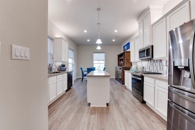 kitchen with a kitchen island, decorative backsplash, light wood-style flooring, appliances with stainless steel finishes, and white cabinetry