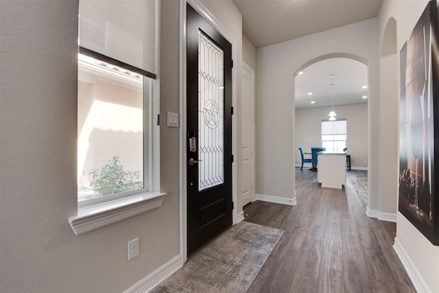 foyer with arched walkways, dark wood-style floors, recessed lighting, and baseboards