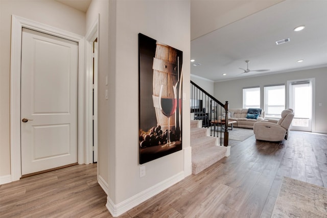 hall featuring stairs, wood finished floors, visible vents, and ornamental molding