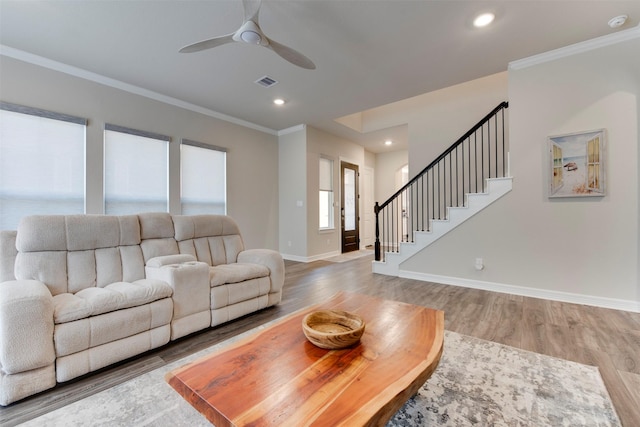 living area with stairway, visible vents, light wood finished floors, and ornamental molding