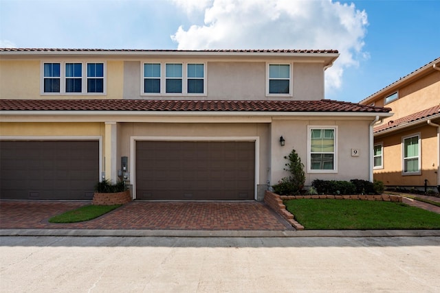 townhome / multi-family property featuring stucco siding, a tiled roof, an attached garage, and decorative driveway