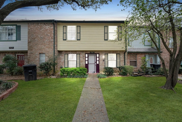 view of property with a front lawn and brick siding