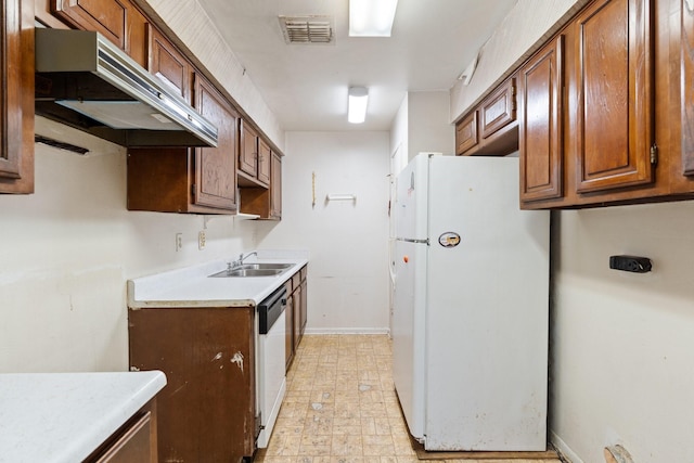 kitchen featuring visible vents, under cabinet range hood, dishwasher, freestanding refrigerator, and a sink