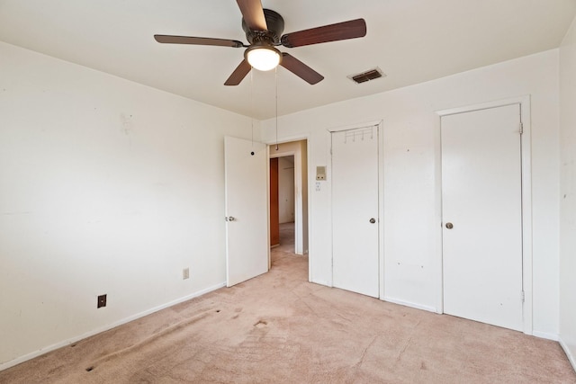 unfurnished bedroom with light carpet, visible vents, ceiling fan, and baseboards