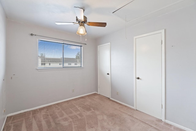 unfurnished bedroom featuring attic access, carpet flooring, a ceiling fan, and baseboards