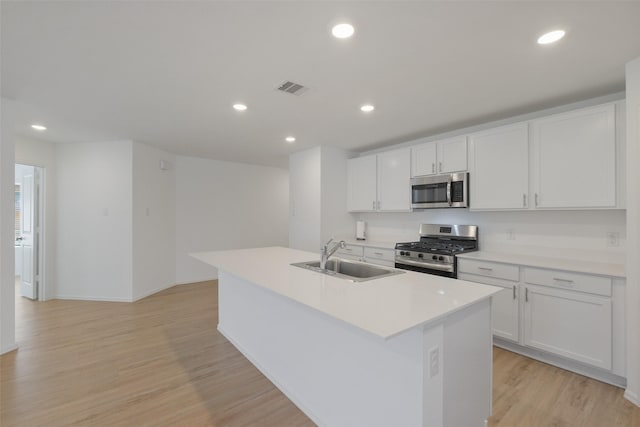 kitchen featuring visible vents, a sink, appliances with stainless steel finishes, light wood-style floors, and a kitchen island with sink