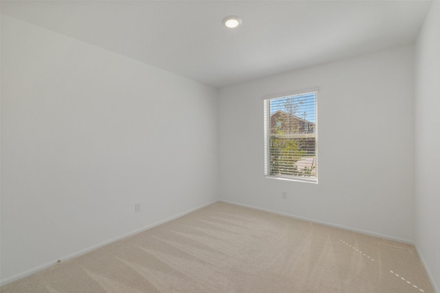 unfurnished room featuring light colored carpet and baseboards