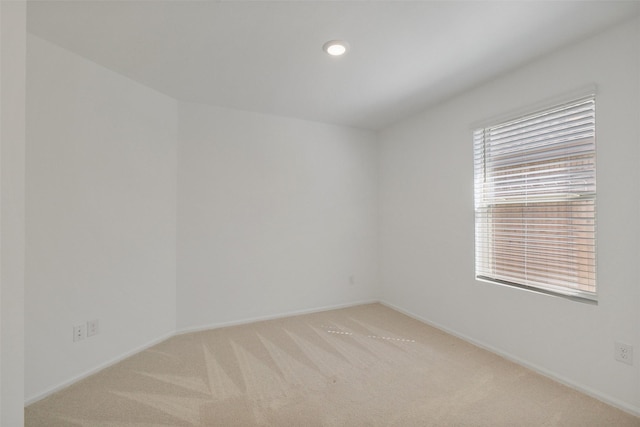 empty room featuring light carpet, recessed lighting, and baseboards