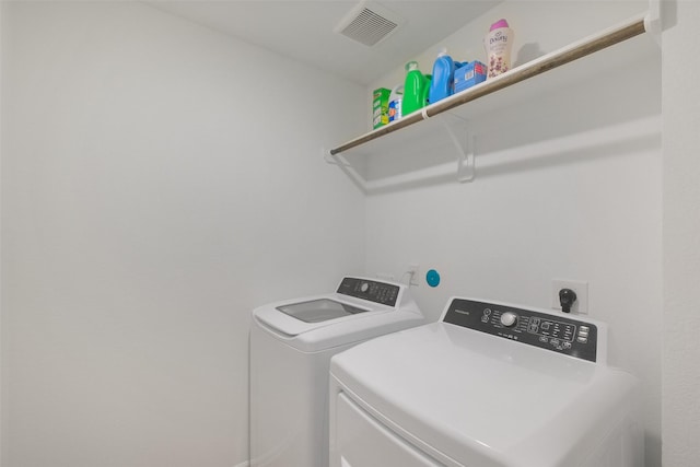 washroom featuring laundry area, visible vents, and washing machine and clothes dryer