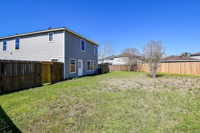 back of house with a yard and a fenced backyard