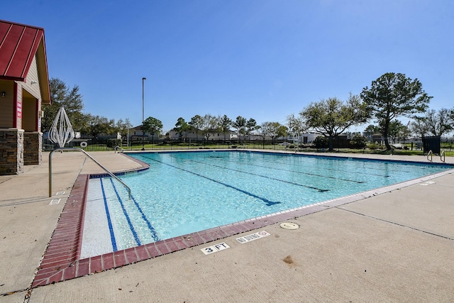 community pool with a patio area and fence