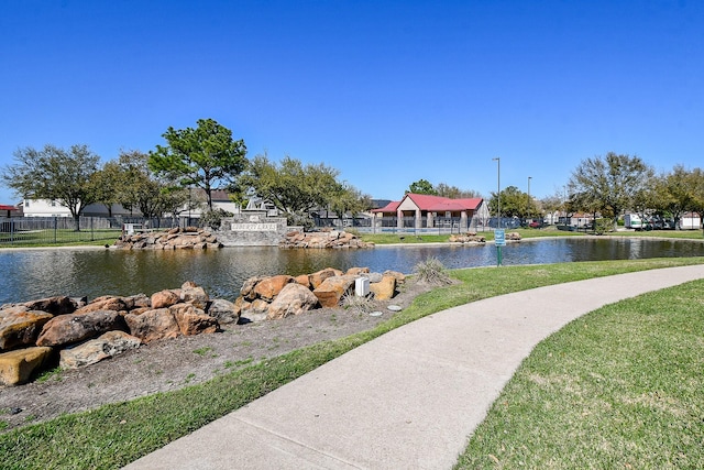 view of property's community featuring a yard, a water view, and fence