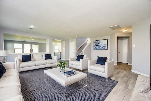 living room featuring baseboards, visible vents, and wood finish floors