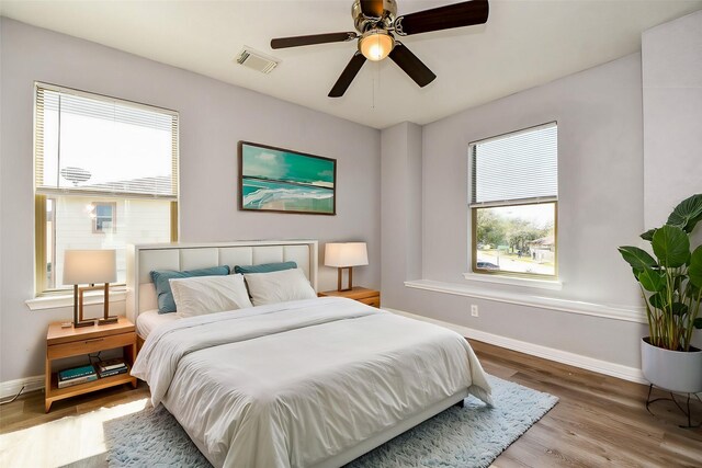 bedroom featuring visible vents, wood finished floors, baseboards, and ceiling fan