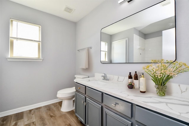 bathroom with toilet, wood finished floors, baseboards, walk in shower, and vanity