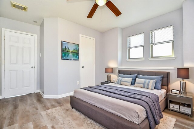 bedroom featuring visible vents, baseboards, wood finished floors, and a ceiling fan