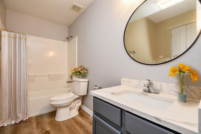 bathroom with visible vents, toilet, wood finished floors, shower / tub combo, and vanity