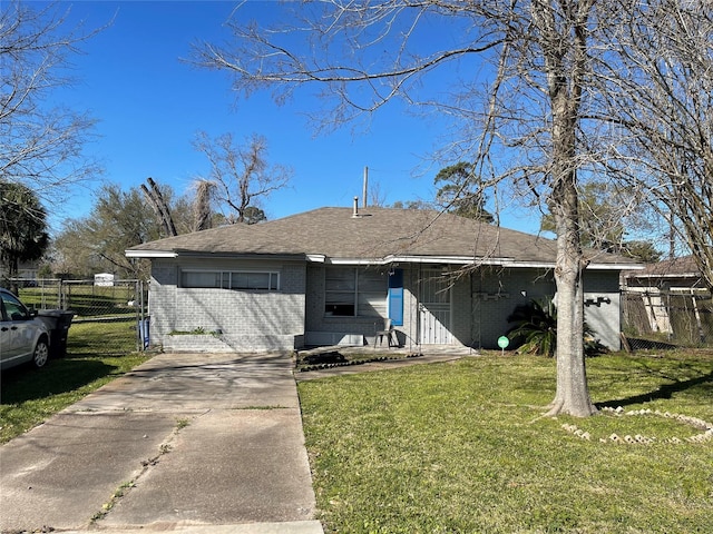 rear view of property with brick siding, fence, concrete driveway, a yard, and a gate