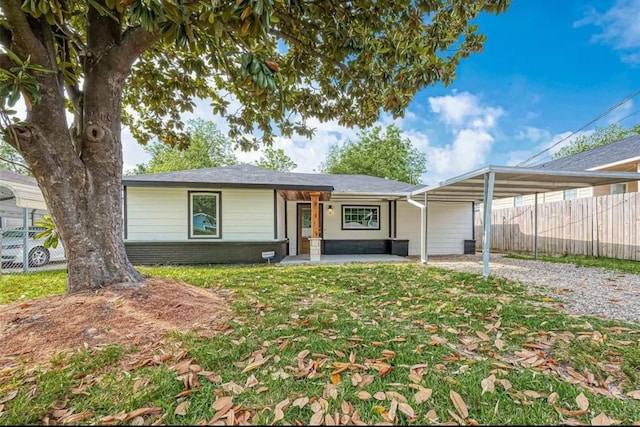 view of front of home featuring driveway, a carport, fence, a front yard, and brick siding