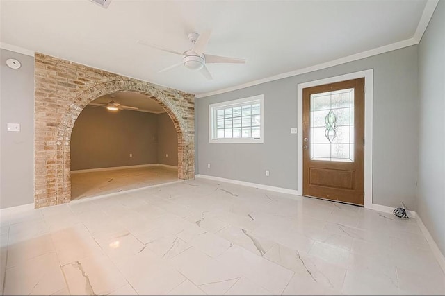 entrance foyer with crown molding, baseboards, arched walkways, and ceiling fan