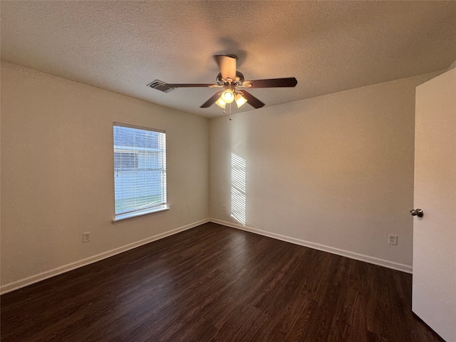 empty room featuring dark wood finished floors, visible vents, a textured ceiling, and baseboards