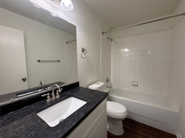 full bath with toilet, wood finished floors, shower / bath combination, vanity, and a textured wall