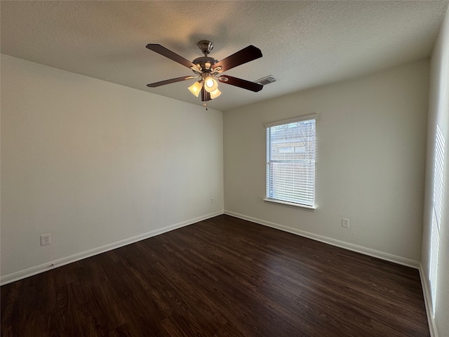 empty room featuring visible vents, baseboards, a textured ceiling, and dark wood-style flooring