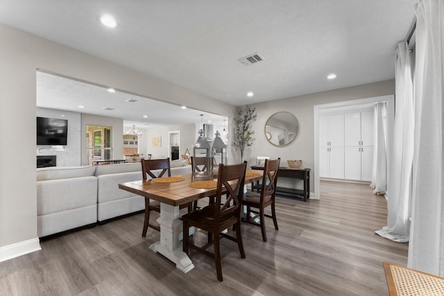 dining room featuring visible vents, a notable chandelier, wood finished floors, and a fireplace