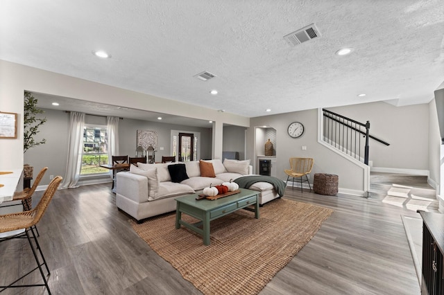 living room featuring visible vents, stairs, and wood finished floors