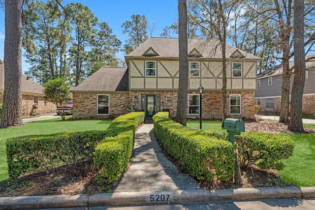 view of front of property featuring stucco siding, brick siding, roof with shingles, and a front lawn