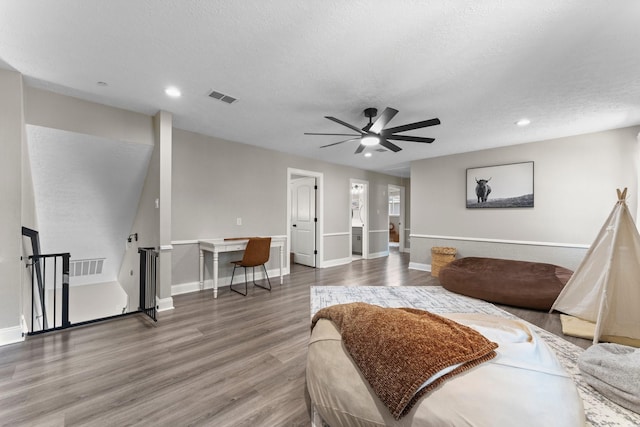 bedroom featuring baseboards, wood finished floors, visible vents, and a textured ceiling