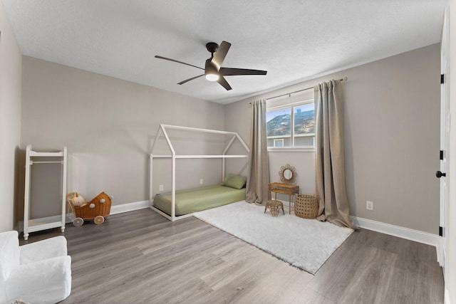 unfurnished bedroom with a textured ceiling, baseboards, and wood finished floors