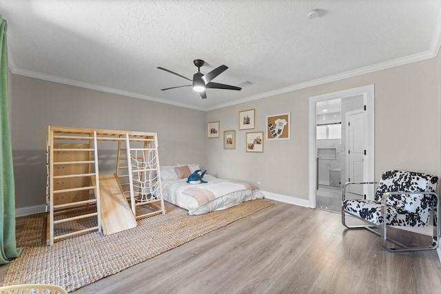 bedroom with a textured ceiling, wood finished floors, visible vents, and ornamental molding