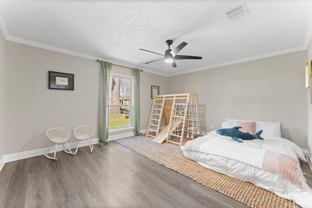 bedroom featuring wood finished floors, baseboards, visible vents, a textured ceiling, and crown molding