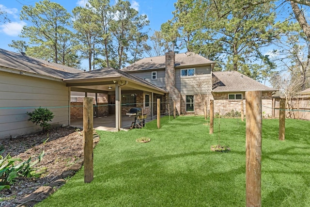 rear view of house with a yard, a patio, a chimney, and fence