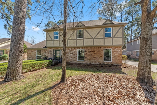 view of front facade featuring stucco siding, brick siding, and a front lawn